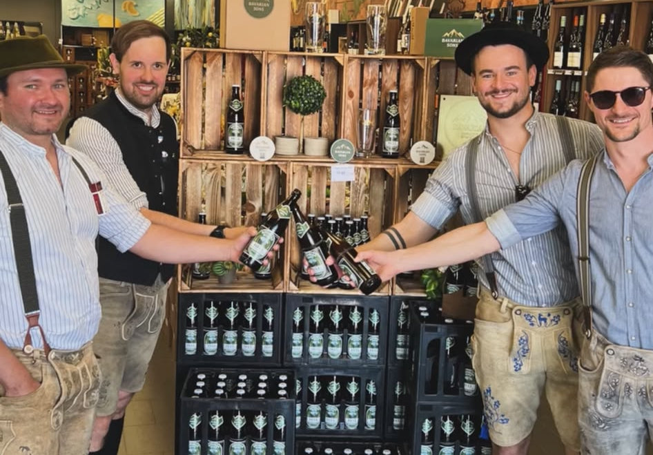 Freunde stoßen strahlend mit Hellem Bier an